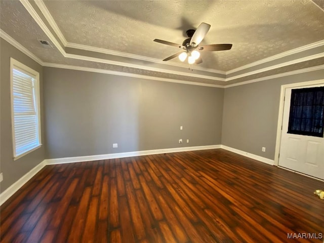 empty room featuring ornamental molding, a textured ceiling, a tray ceiling, ceiling fan, and dark hardwood / wood-style floors