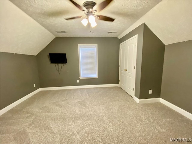 additional living space with ceiling fan, carpet floors, a textured ceiling, and vaulted ceiling