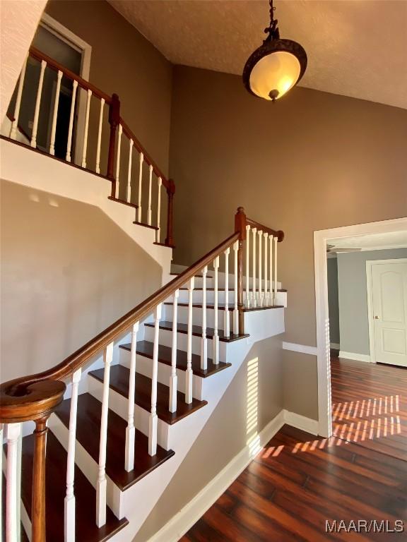 stairs with wood-type flooring and a high ceiling