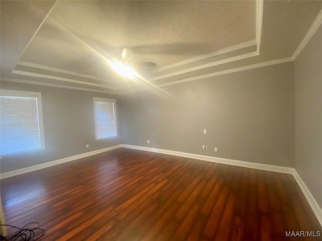 spare room featuring ceiling fan, a raised ceiling, ornamental molding, and dark wood-type flooring