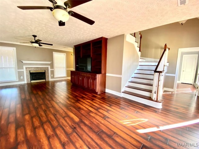 unfurnished living room with ceiling fan, a textured ceiling, and dark wood-type flooring