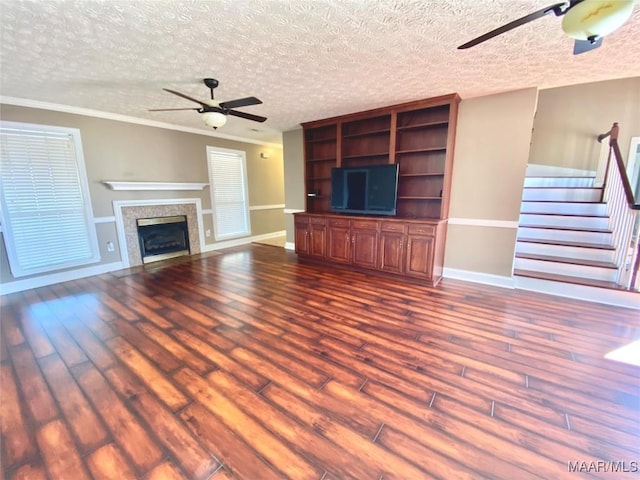 unfurnished living room with ceiling fan, hardwood / wood-style floors, a textured ceiling, and ornamental molding