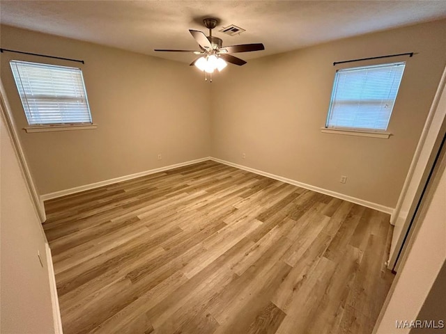 empty room with light hardwood / wood-style flooring, plenty of natural light, and ceiling fan