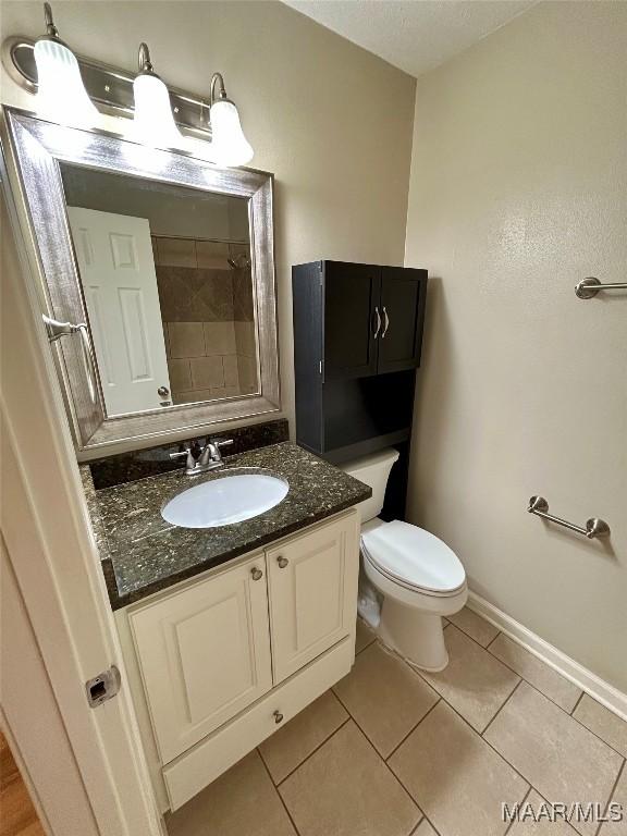 bathroom with tile patterned floors, vanity, toilet, and tiled shower