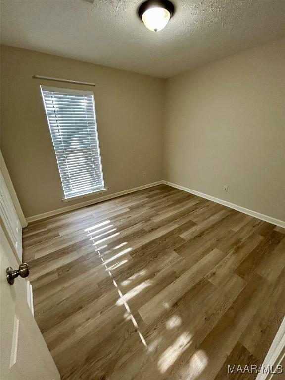 unfurnished room with wood-type flooring and a textured ceiling