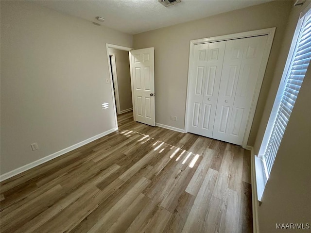 unfurnished bedroom featuring multiple windows, a closet, and hardwood / wood-style floors