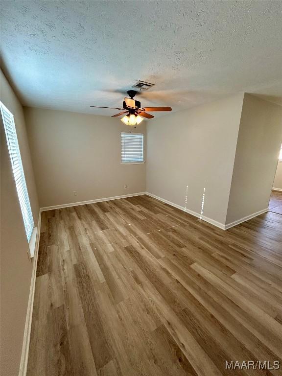 empty room featuring ceiling fan, a textured ceiling, and light hardwood / wood-style flooring