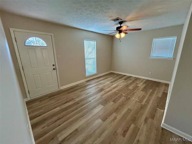 foyer entrance with ceiling fan, light hardwood / wood-style floors, and a textured ceiling