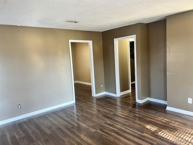 empty room with dark wood-type flooring and a textured ceiling