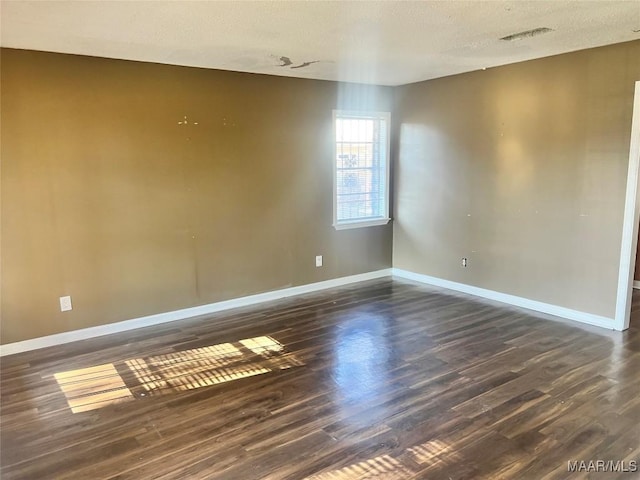 spare room with dark hardwood / wood-style floors and a textured ceiling