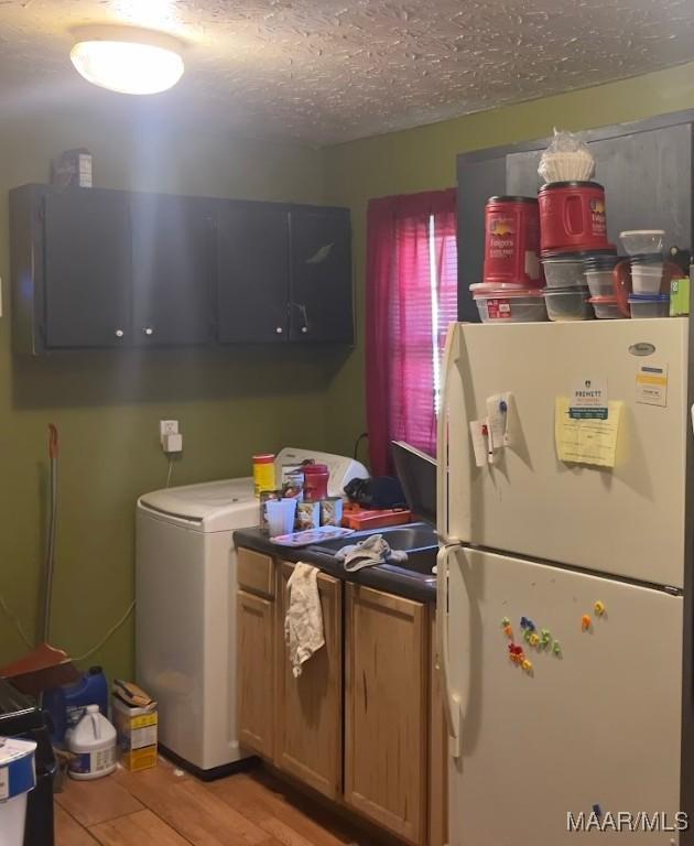 kitchen with washer / dryer, white refrigerator, a textured ceiling, and light hardwood / wood-style floors