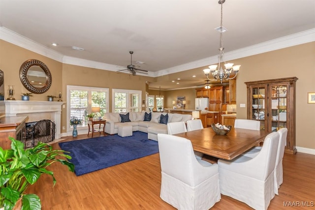 dining room with ceiling fan with notable chandelier, light wood-type flooring, and crown molding