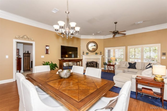 dining space featuring ceiling fan with notable chandelier, ornamental molding, and hardwood / wood-style flooring