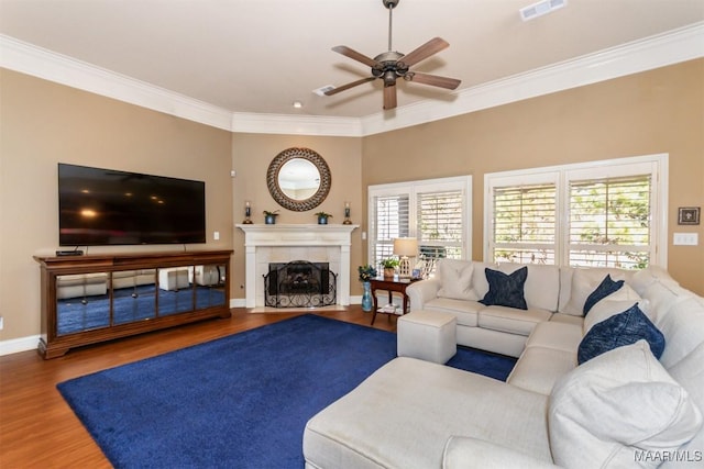 living room with ceiling fan, hardwood / wood-style floors, ornamental molding, and a tiled fireplace