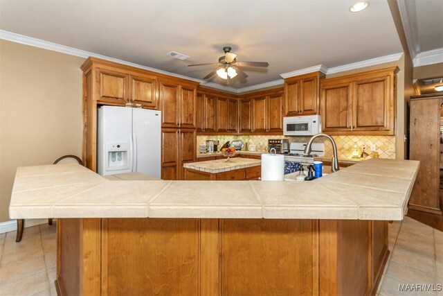 kitchen with white appliances, ceiling fan, ornamental molding, decorative backsplash, and a kitchen island