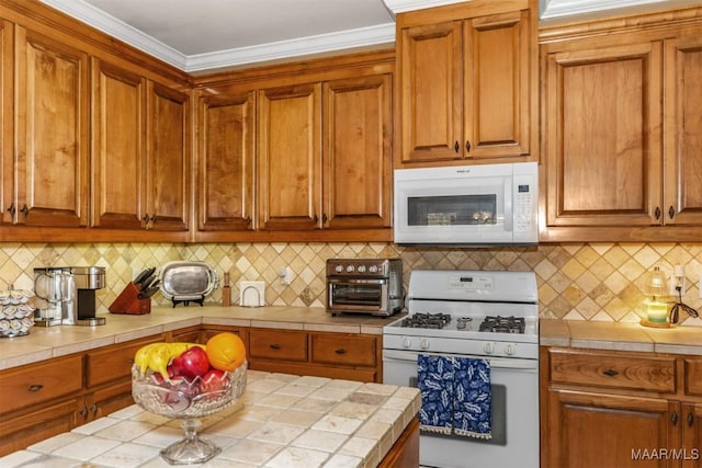 kitchen with white appliances, ornamental molding, tile countertops, and decorative backsplash