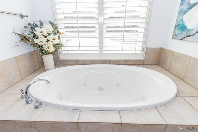 bathroom featuring a relaxing tiled tub and a healthy amount of sunlight