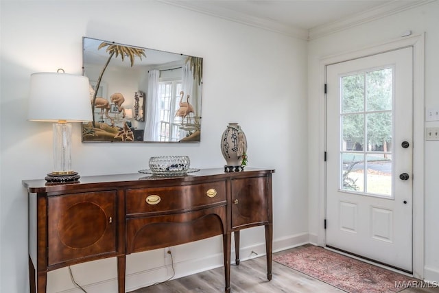 foyer with wood finished floors, baseboards, and ornamental molding