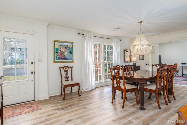 dining room featuring crown molding, light wood-type flooring, visible vents, baseboards, and a notable chandelier