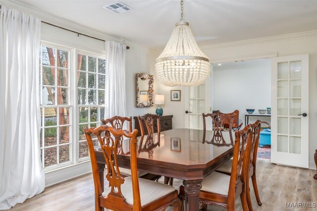 dining space with french doors, crown molding, a chandelier, and light hardwood / wood-style flooring