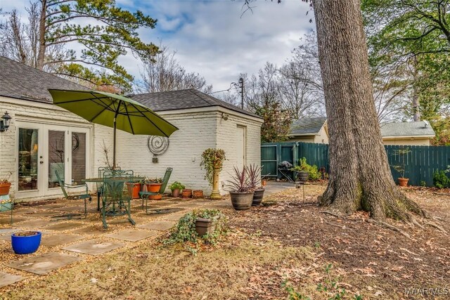 exterior space featuring a patio, brick siding, french doors, and fence