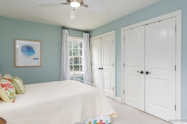 bedroom with two closets, light colored carpet, and ceiling fan