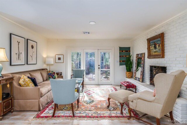 living room featuring french doors, ornamental molding, a fireplace, and light hardwood / wood-style floors