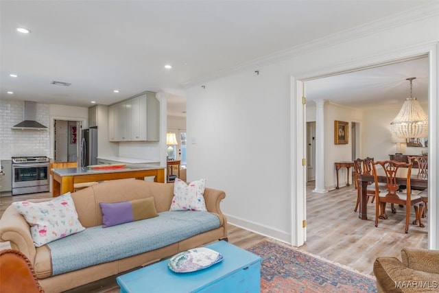 living area with visible vents, baseboards, crown molding, light wood finished floors, and recessed lighting