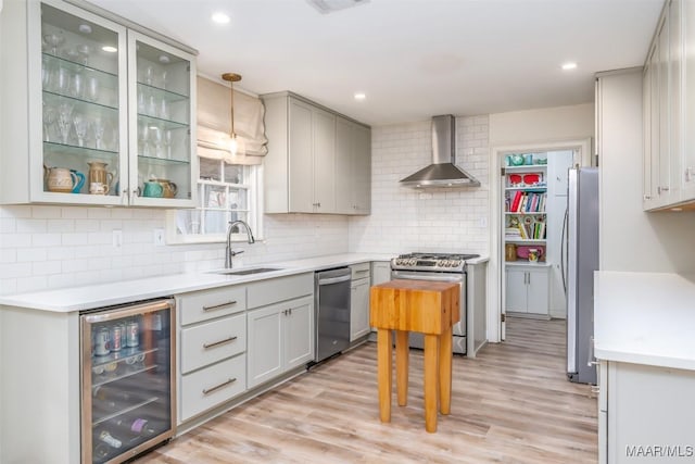 kitchen with light countertops, wall chimney exhaust hood, stainless steel appliances, beverage cooler, and a sink