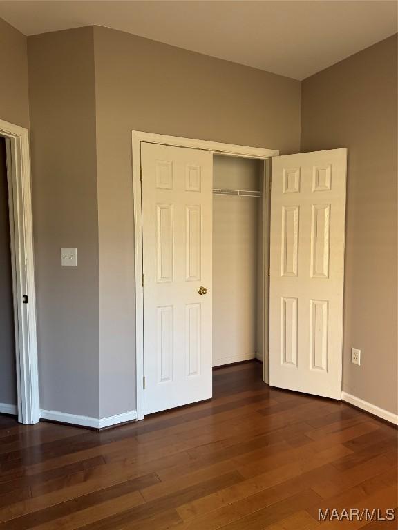 unfurnished bedroom featuring a closet and dark hardwood / wood-style floors