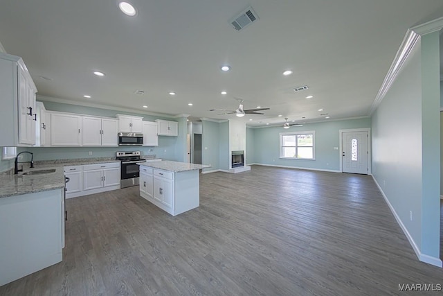 kitchen with stainless steel appliances, white cabinets, a center island, and sink