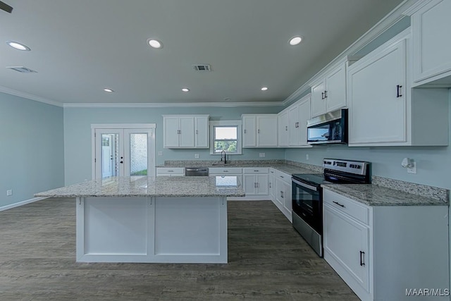 kitchen featuring stainless steel appliances, white cabinetry, light stone counters, and a kitchen island