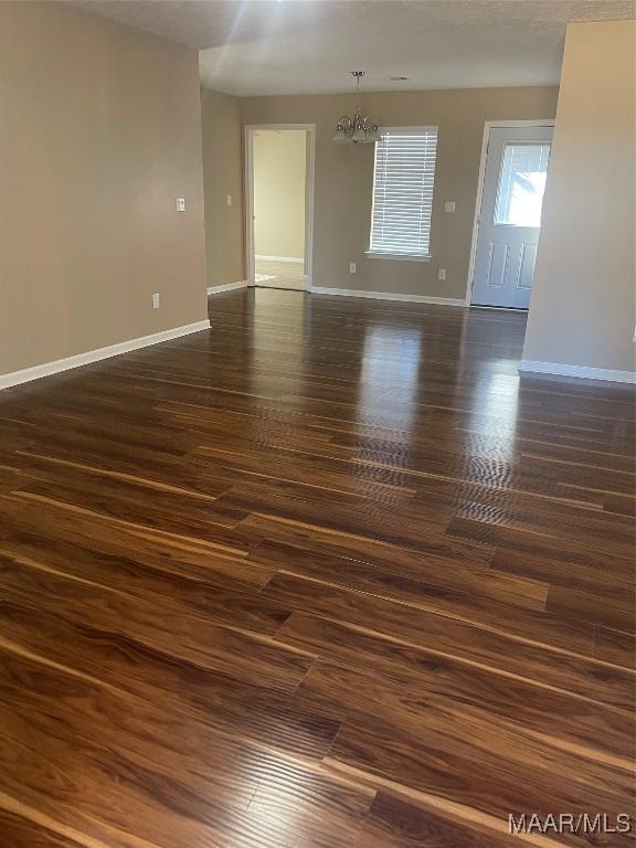 unfurnished room featuring dark hardwood / wood-style flooring and a notable chandelier