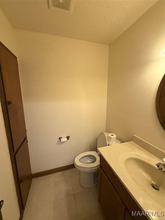 bathroom featuring toilet, vanity, and tile patterned flooring