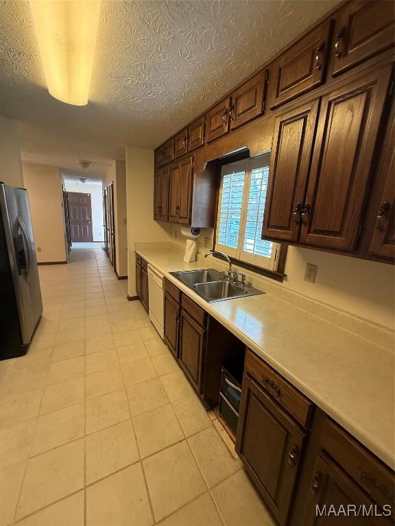 kitchen with dishwasher, a textured ceiling, stainless steel fridge, dark brown cabinetry, and sink