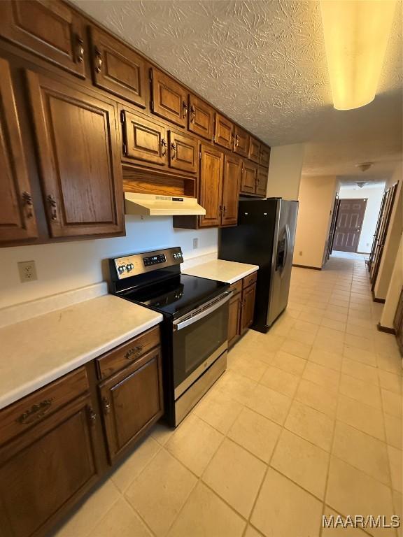 kitchen featuring light tile patterned flooring, a textured ceiling, and appliances with stainless steel finishes