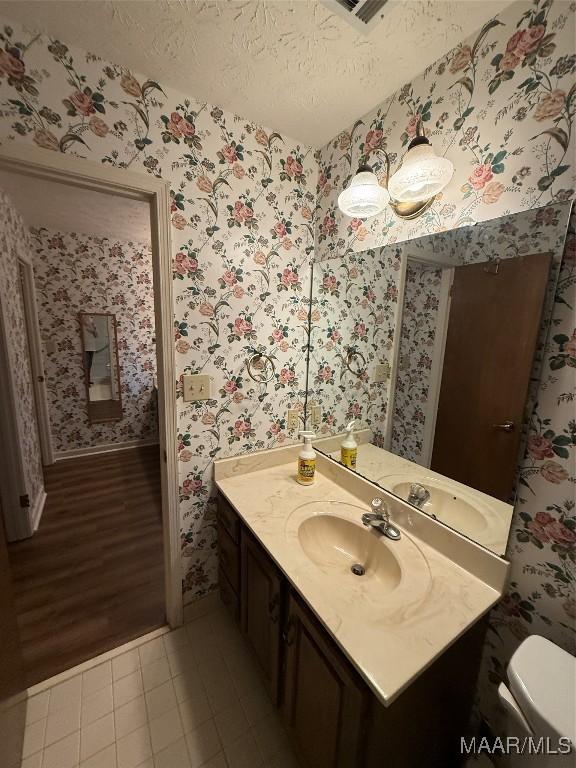 bathroom featuring toilet, a textured ceiling, tile patterned floors, and vanity