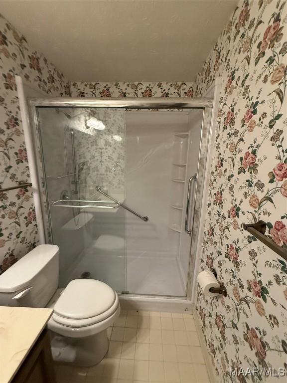 bathroom with an enclosed shower, vanity, and toilet