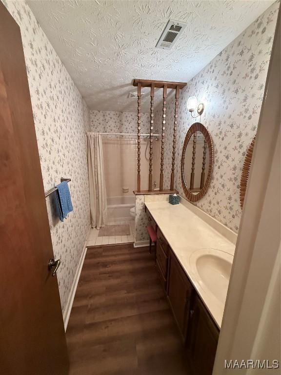 bathroom with hardwood / wood-style flooring, a textured ceiling, shower / bath combination with curtain, and vanity