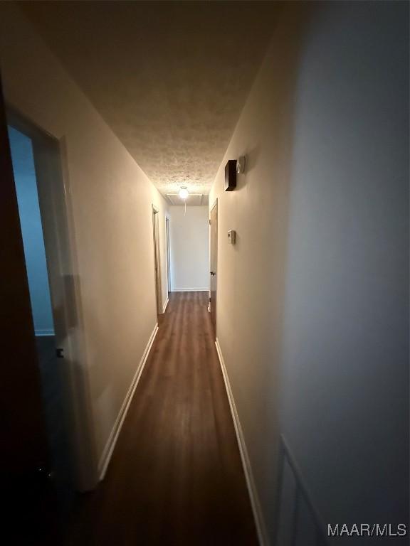 hall with a textured ceiling and dark wood-type flooring