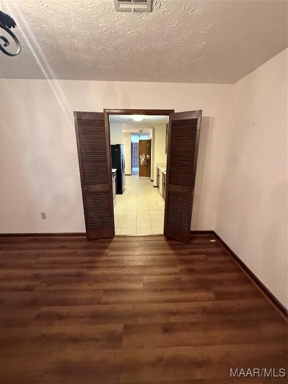 empty room with a textured ceiling and wood-type flooring