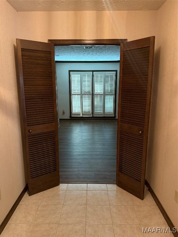 tiled empty room featuring a textured ceiling