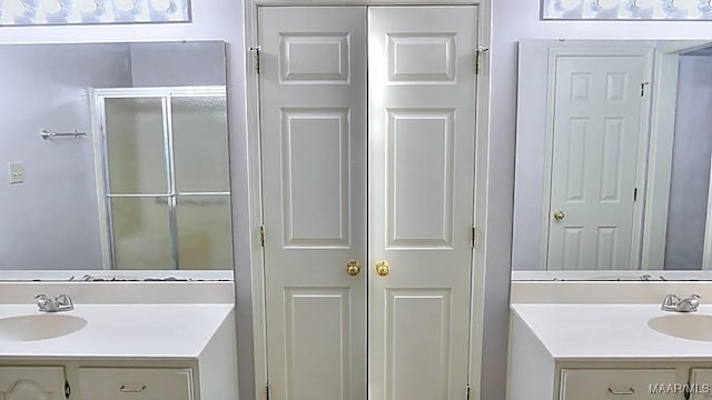 bathroom featuring a shower with door and vanity