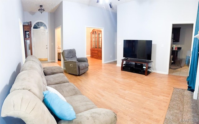 living room featuring a towering ceiling, wood-type flooring, and ceiling fan