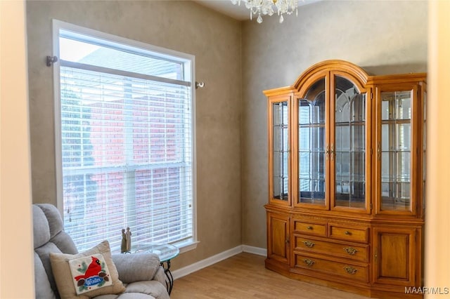 sitting room with an inviting chandelier, a wealth of natural light, and light hardwood / wood-style floors