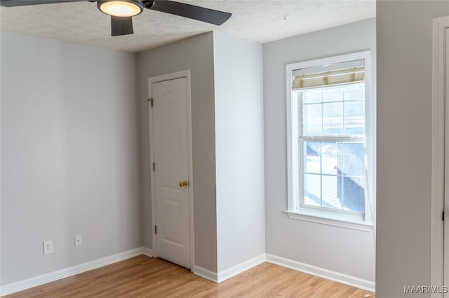 spare room with ceiling fan, light hardwood / wood-style flooring, and a textured ceiling