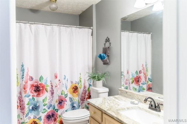 bathroom with vanity, toilet, and a textured ceiling