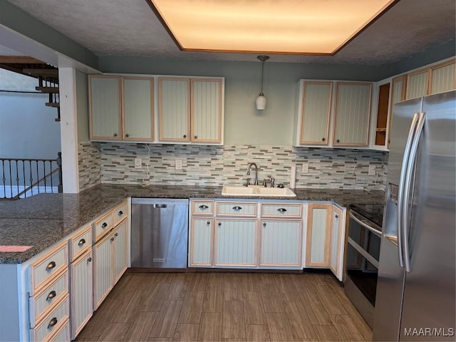 kitchen with appliances with stainless steel finishes, hanging light fixtures, kitchen peninsula, decorative backsplash, and sink