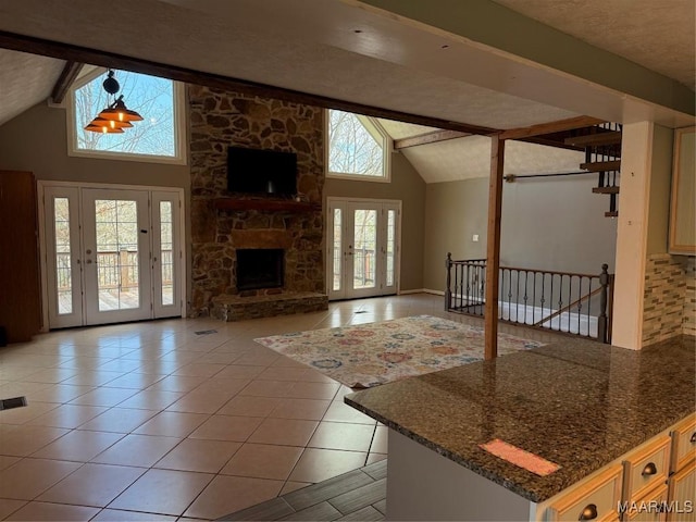 unfurnished living room featuring high vaulted ceiling, beam ceiling, light tile patterned floors, and a stone fireplace