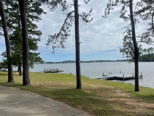 view of dock with a yard and a water view